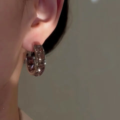 Smoky brown crystal huggie hoop earring worn on right ear close-up