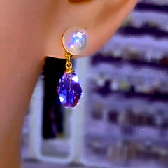 Gold tone iridescent pearl purple faceted teardrop crystal drop earring worn on ear (side view)