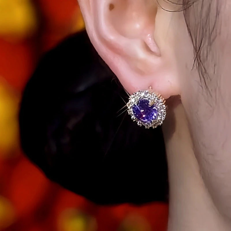 Purple gemstone halo stud earring worn on woman's earlobe