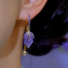 Purple crystal leaf drop hoop earring worn on human ear close-up