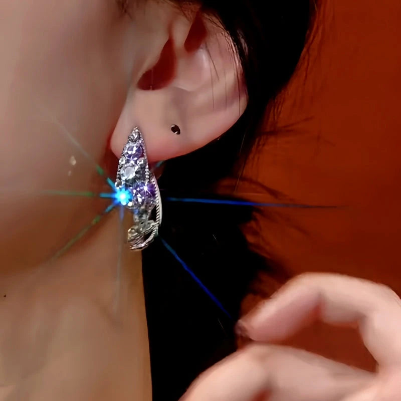 Sparkling silver teardrop crystal drop earring worn on ear, front close-up