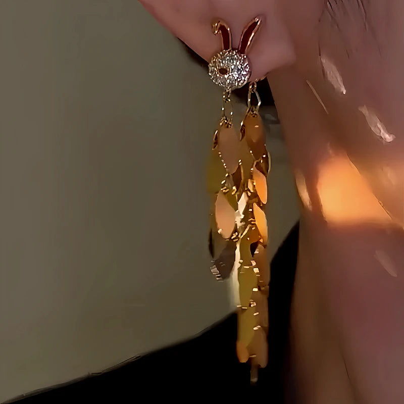 Close-up of gold rabbit leaf tassel dangle earring worn on ear