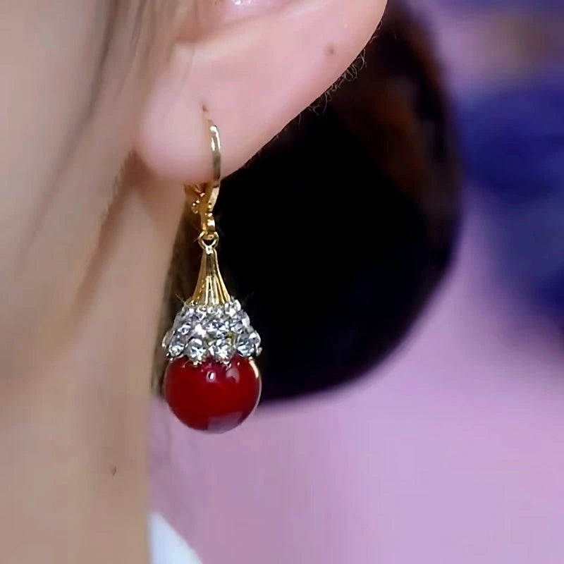 Model showcasing the dangle and style of the 14K Gold-Plated Red Bead Earrings