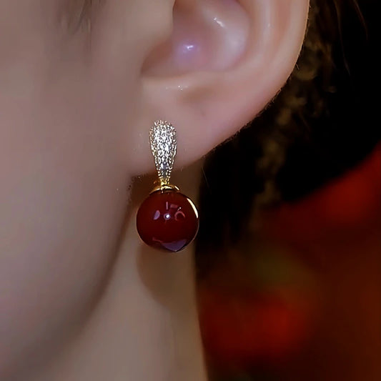 Model showcasing the dangle and style of the 14K Gold-Plated Red Bead Earrings
