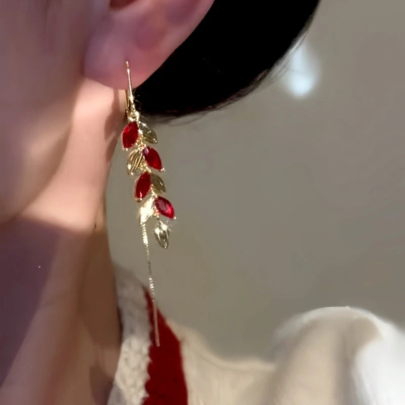 Close up of red zircon leaf gold ear threader drop earring on ear