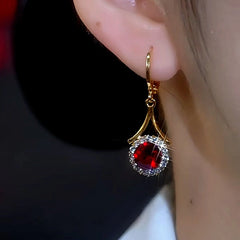 Side view of gold ruby red crystal halo drop earring on a woman's ear