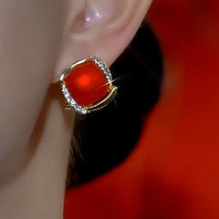 Angled view of red cushion-cut gold crystal stud earring on ear