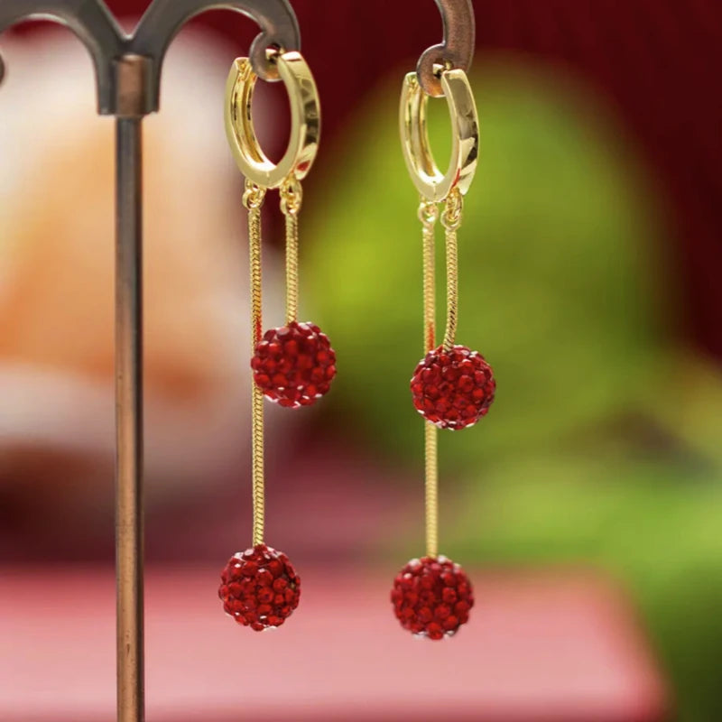 Angled view of the 14K Gold-Plated Red Diamond Ball Tassel Earrings