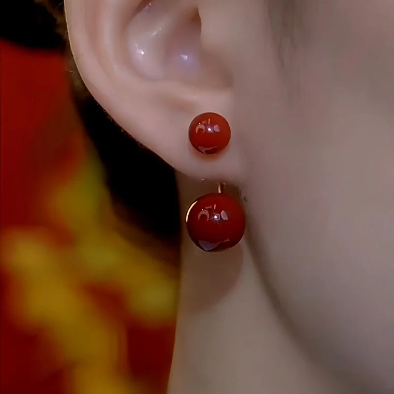 Model showcasing the dangle and style of the 14K Gold-Plated Red Double Bead Earrings