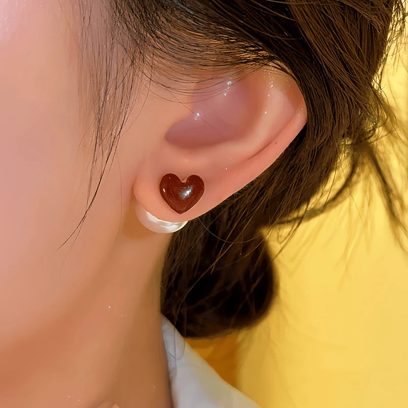 Model showcasing the dangle and style of the 14K Gold-Plated Red Heart Bead Earrings