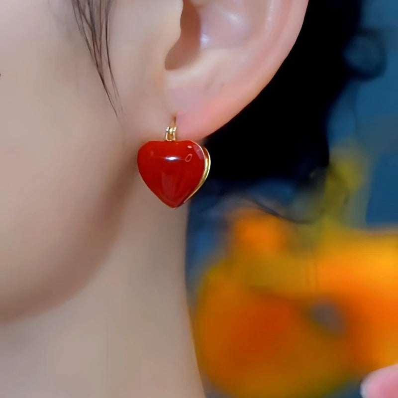 Model showcasing the dangle and style of the 14K Gold-Plated Red Heart Earrings
