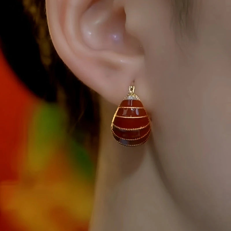 Model showcasing the dangle and style of the 14K Gold-Plated Red Oil Drop Bag Earrings