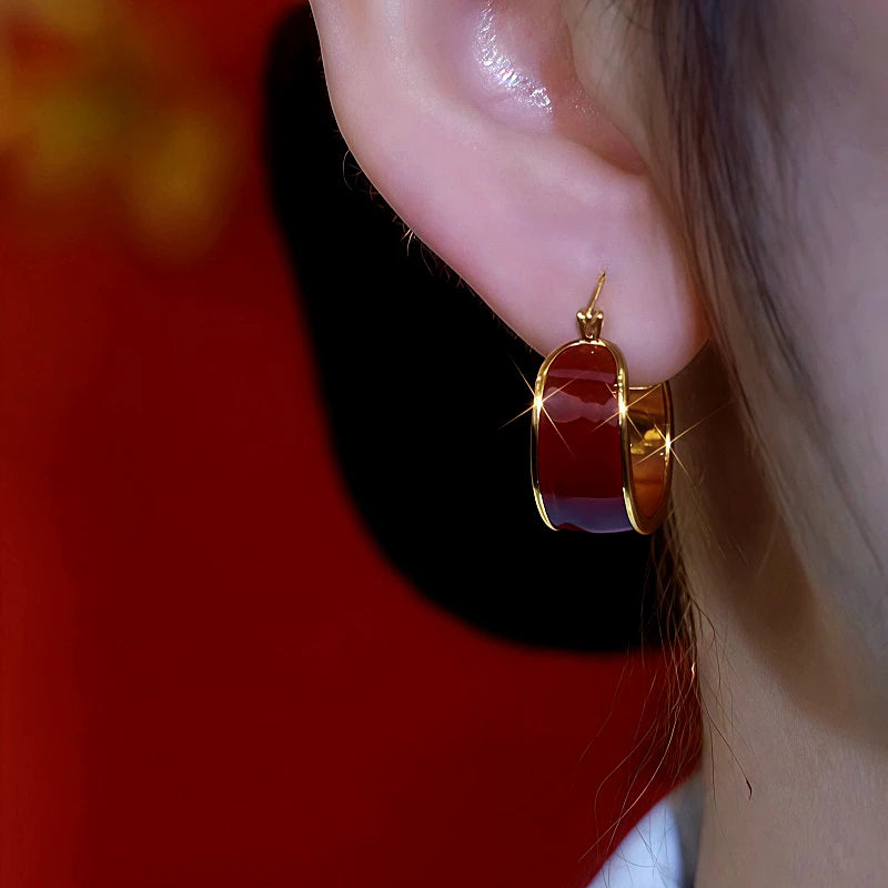 Model showcasing the dangle and style of the 14K Gold-Plated Red Oil Drop Hoop Earrings