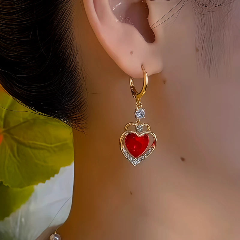 Model showcasing the dangle and style of the 14K Gold-Plated Red Stone Heart Earrings