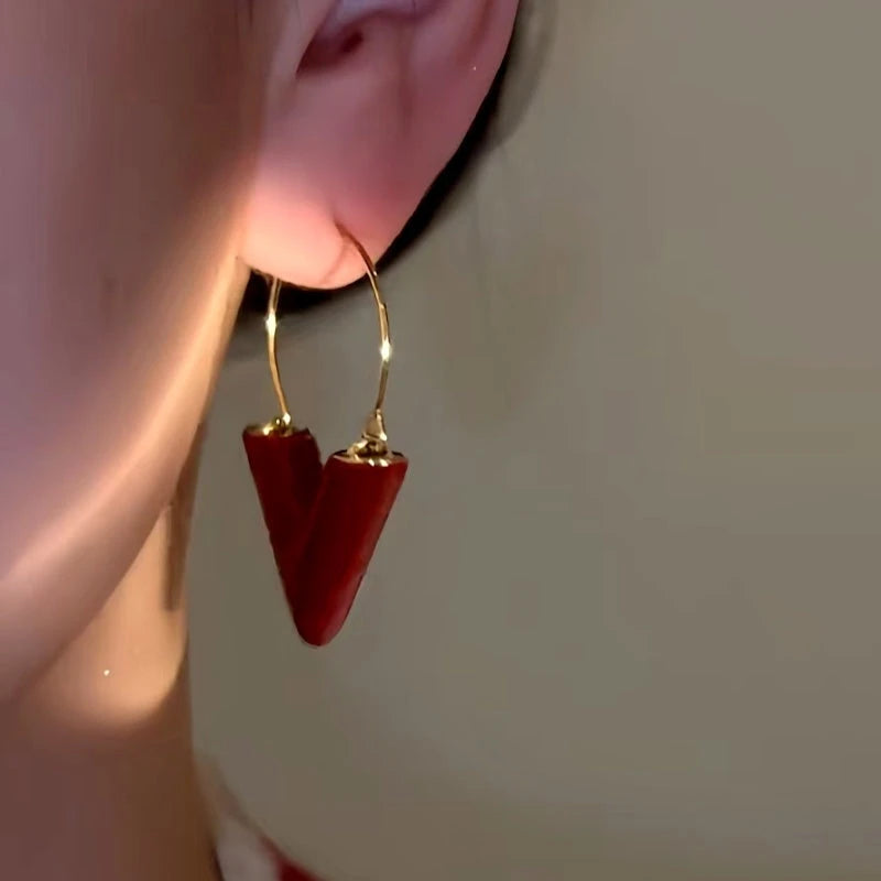 Model showcasing the dangle and style of the 14K Gold-Plated Red V Letter Fashion Earrings
