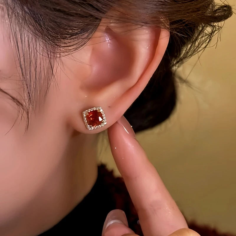 Model showcasing the dangle and style of the 14K Gold-Plated Red Zircon Stud Earrings