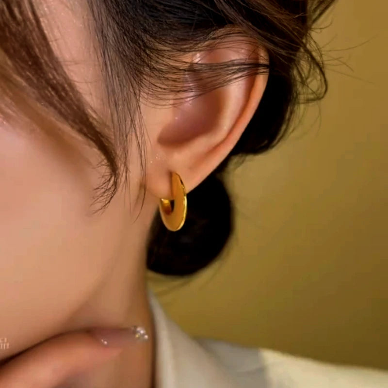 Model showcasing the dangle and style of the 14K Gold-Plated Smooth Flat Hoop Earrings