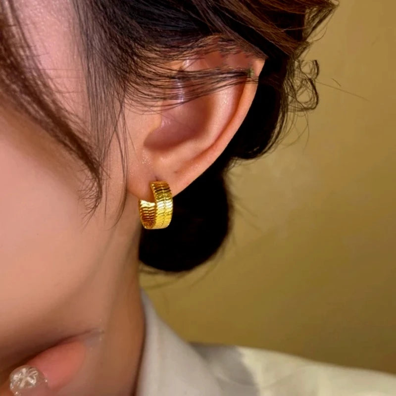 Model showcasing the dangle and style of the 14K Gold-Plated Snake Bone Pattern Little Hoop Earrings