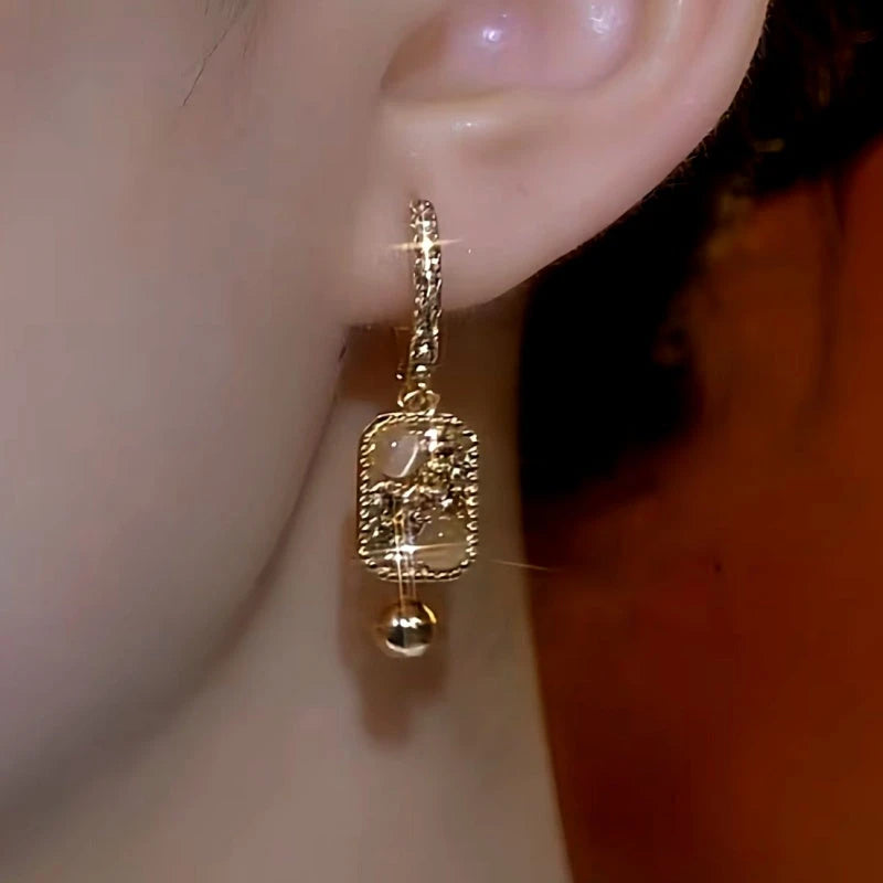 Model showcasing the dangle and style of the 14K Gold-Plated Square Cat's Eye Earrings