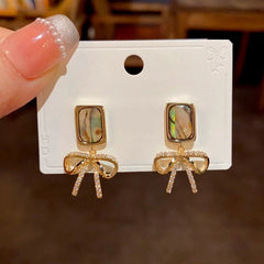 Angled view of the 14K Gold-Plated Square Colored Shell Zircon Bow Earrings