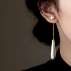 Model showcasing the dangle and style of the 14K Gold-Plated Textured Water Drop Pearl Earrings