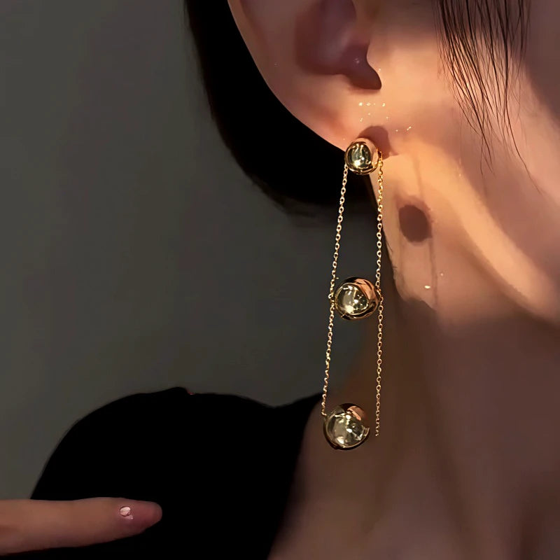 Model showcasing the dangle and style of the 14K Gold-Plated Three-Ball Chain Earrings