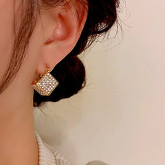 Model showcasing the dangle and style of the 14K Gold-Plated Three-Dimensional Square Earrings