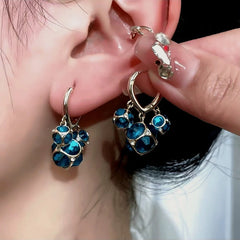 Model showcasing the dangle and style of the 14K Gold-Plated Three Cat-Eye Ball Earrings