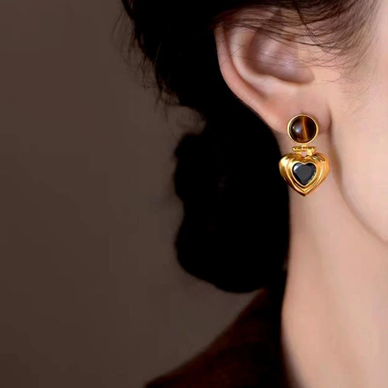 Model showcasing the dangle and style of the 14K Gold-Plated Tiger Eye Heart-Shaped Black Zircon Earrings
