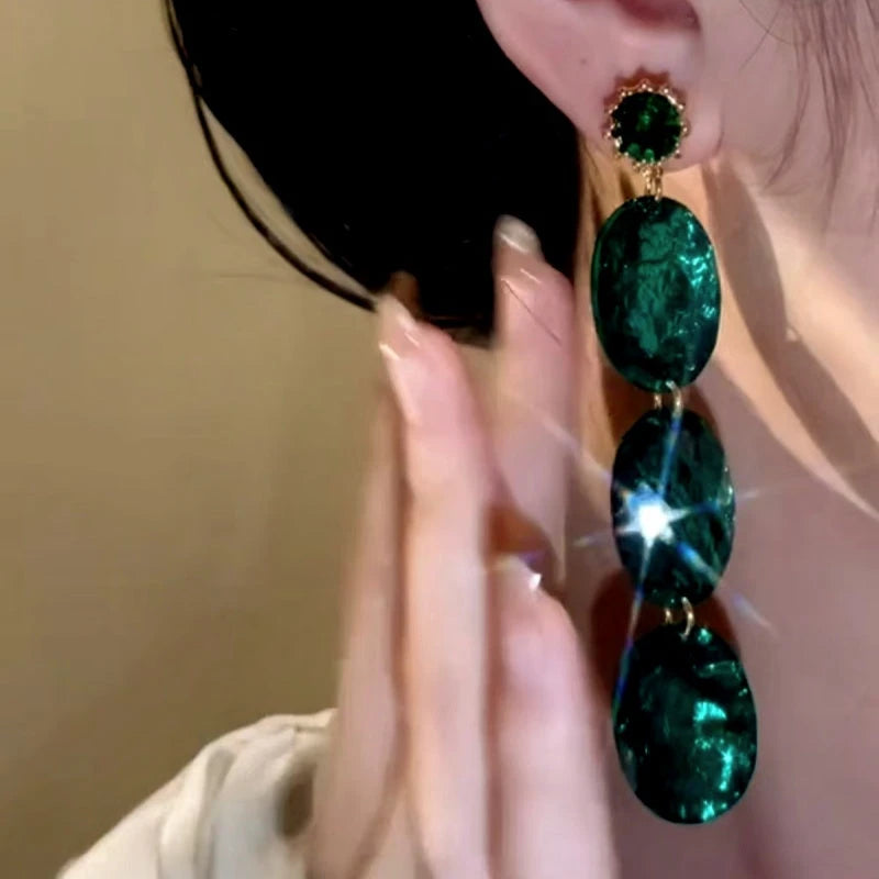 Model showcasing the dangle and style of the 14K Gold-Plated Vintage Emerald Diamond Oval Earrings