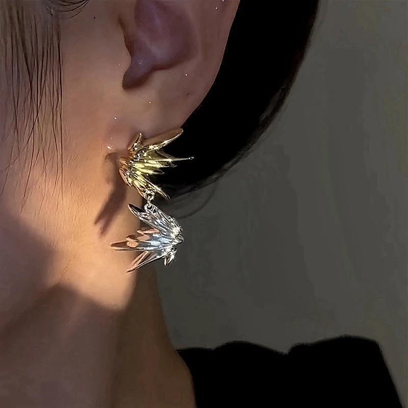 Two-tone gold silver spiky starburst drop earring on ear, angled close-up