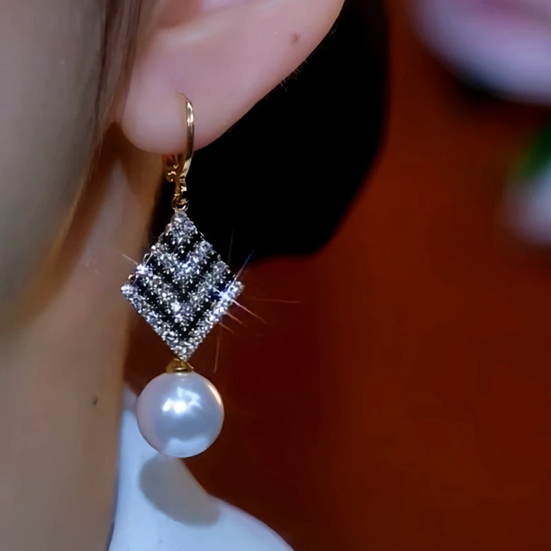 Model showcasing the dangle and style of the 14K Gold-Plated Zircon Black And White Diamond Pearl Earrings