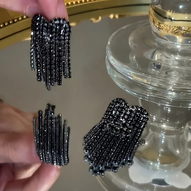 Angled view of the 14K Gold-Plated Zircon Black Diamond Heart Tassel Earrings