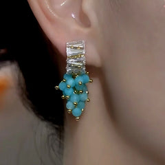 Model showcasing the dangle and style of the 14K Gold-Plated Zircon Blue Bead Tassel Earrings