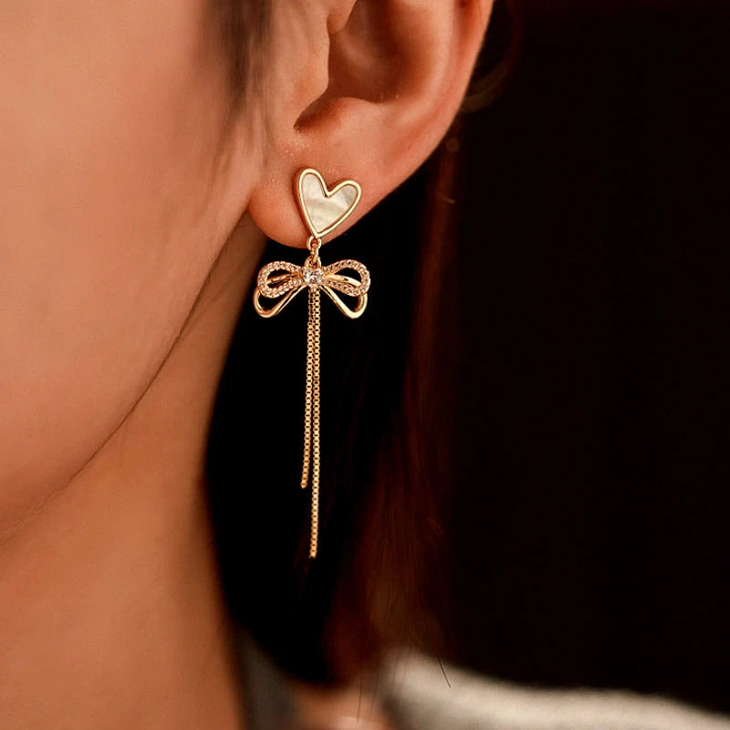 Angled view of the 14K Gold-Plated Zircon Bow Heart-Design Tassel Earrings
