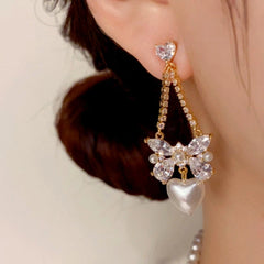 Model showcasing the dangle and style of the 14K Gold-Plated Zircon Bow Heart Pearl Earrings