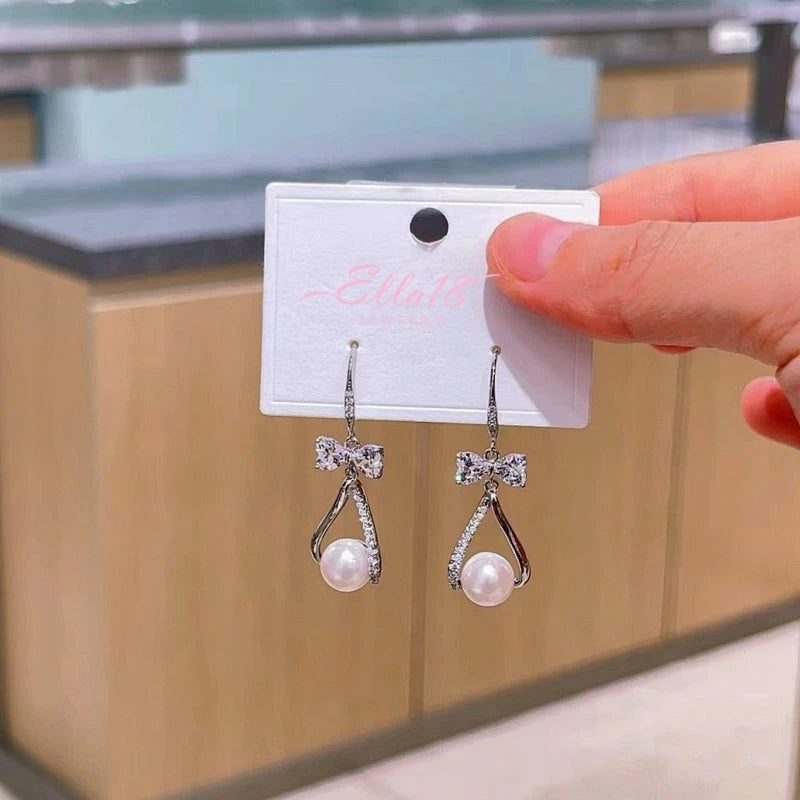 Model showcasing the dangle and style of the 14K Gold-Plated Zircon Bow Pearl Ear Hook Earrings