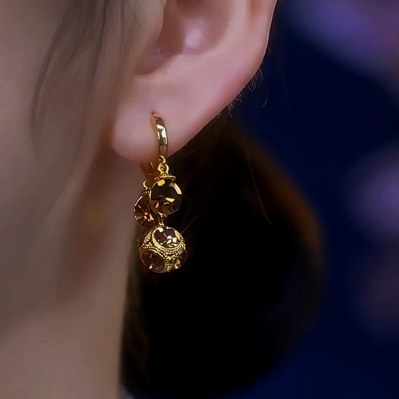 Model showcasing the dangle and style of the 14K Gold-Plated Zircon Brown Diamond Ball Tassel Earrings