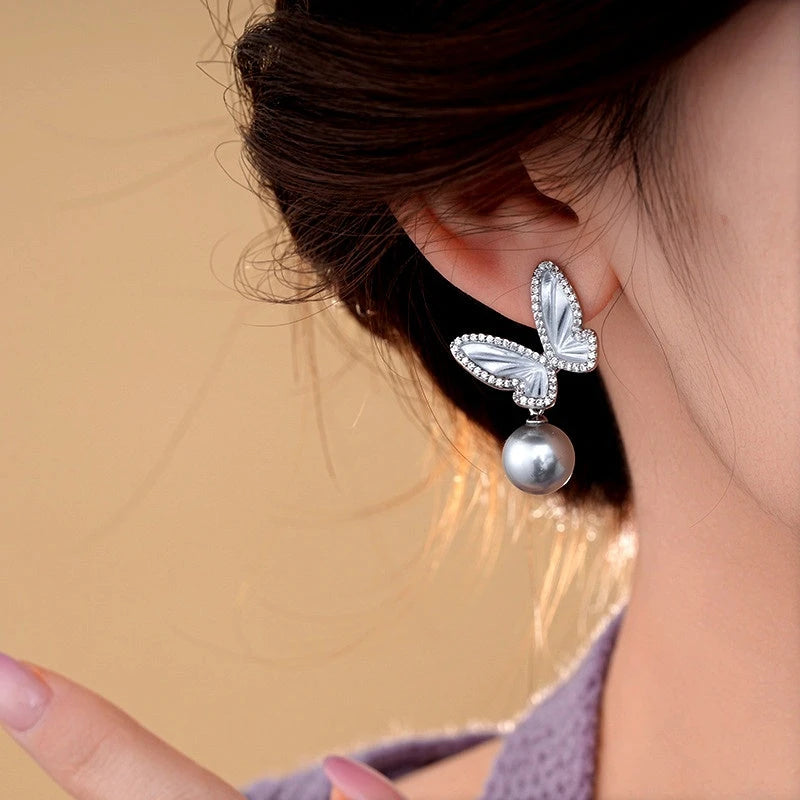 Model showcasing the dangle and style of the 14K Gold-Plated Zircon Butterfly Gray Pearl Earrings