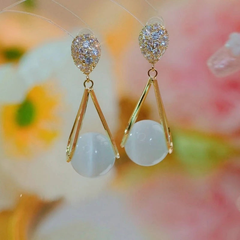 Model showcasing the dangle and style of the 14K Gold-Plated Zircon Cat's Eye Bead Earrings