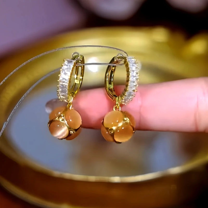 Angled view of the 14K Gold-Plated Zircon Cat's Eye Stone Ball Earrings