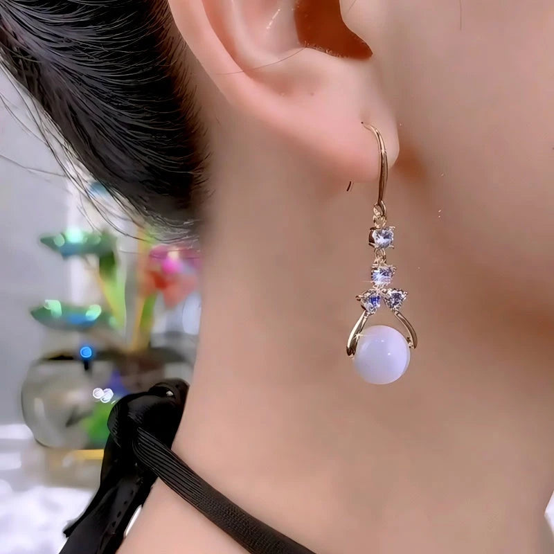 Model showcasing the dangle and style of the 14K Gold-Plated Zircon Diamond Cat's Eye Bead Ear Hook Earrings