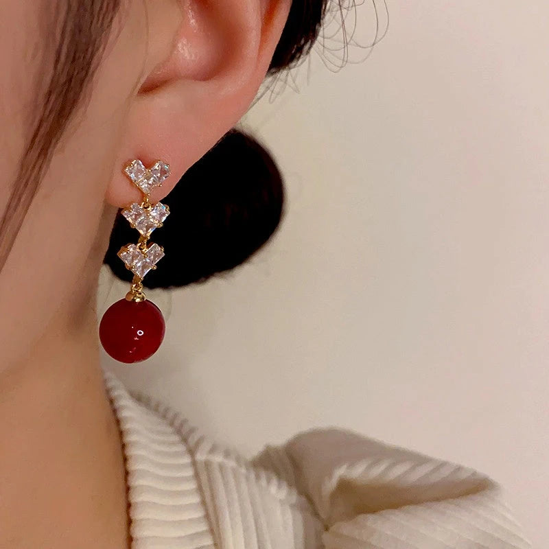 Model showcasing the dangle and style of the 14K Gold-Plated Zircon Diamond Heart Pearl Tassel Earrings
