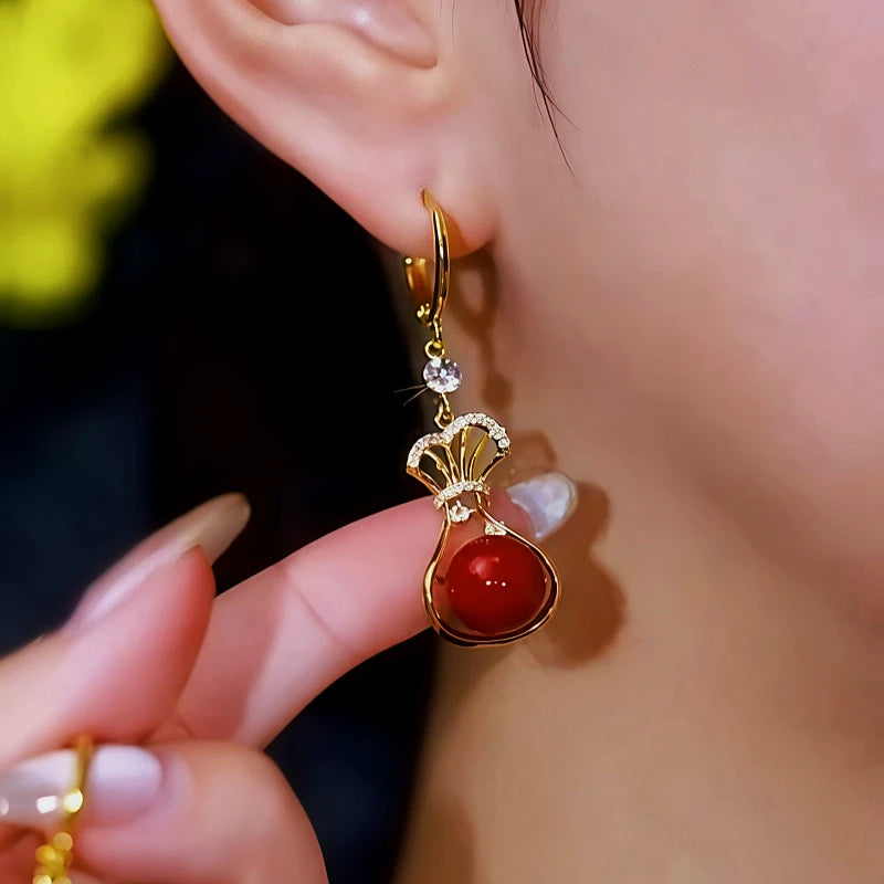 Model showcasing the dangle and style of the 14K Gold-Plated Zircon Diamond Red Lucky Bag Earrings