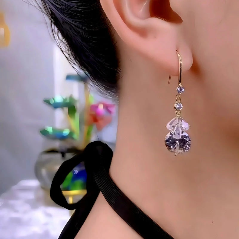 Elegant purple crystal drop dangle earring with gold hook worn on woman's ear