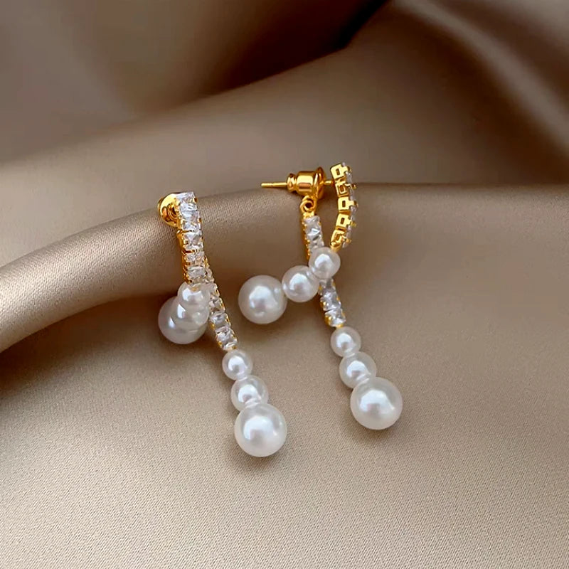 Model showcasing the dangle and style of the 14K Gold-Plated Zircon Face-Slimming Pearl Earrings