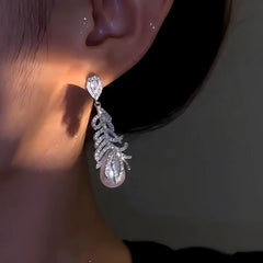 Model showcasing the dangle and style of the 14K Gold-Plated Zircon Feather Pearl Earrings