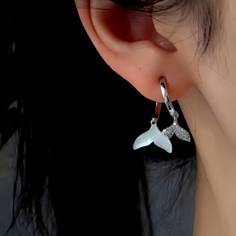 Model showcasing the dangle and style of the 14K Gold-Plated Zircon Fishtail Cross Earrings