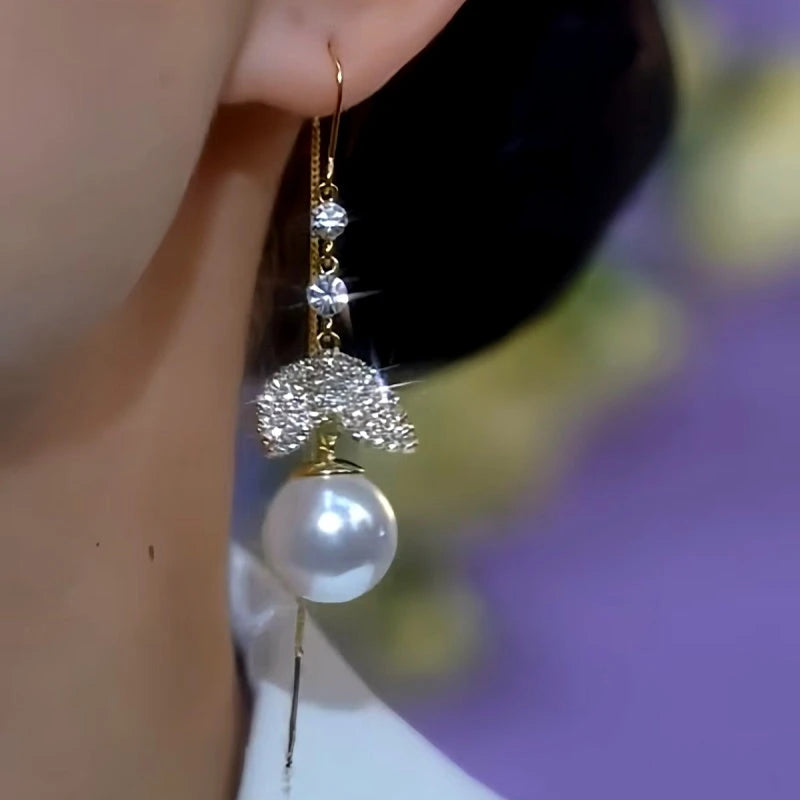 Model showcasing the dangle and style of the 14K Gold-Plated Zircon Fishtail Pearl Threader Earrings