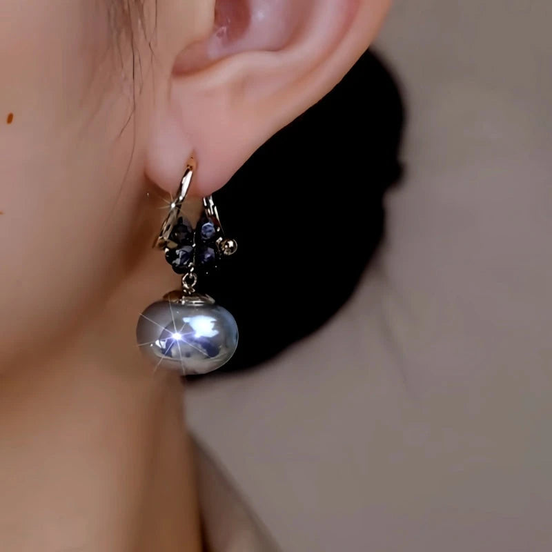 Model showcasing the dangle and style of the 14K Gold-Plated Zircon Flower Oval Pearl Earrings